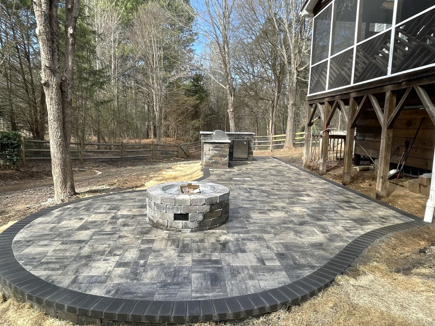 A large paver patio with a firepit and outdoor kitchen in Charlotte, NC.